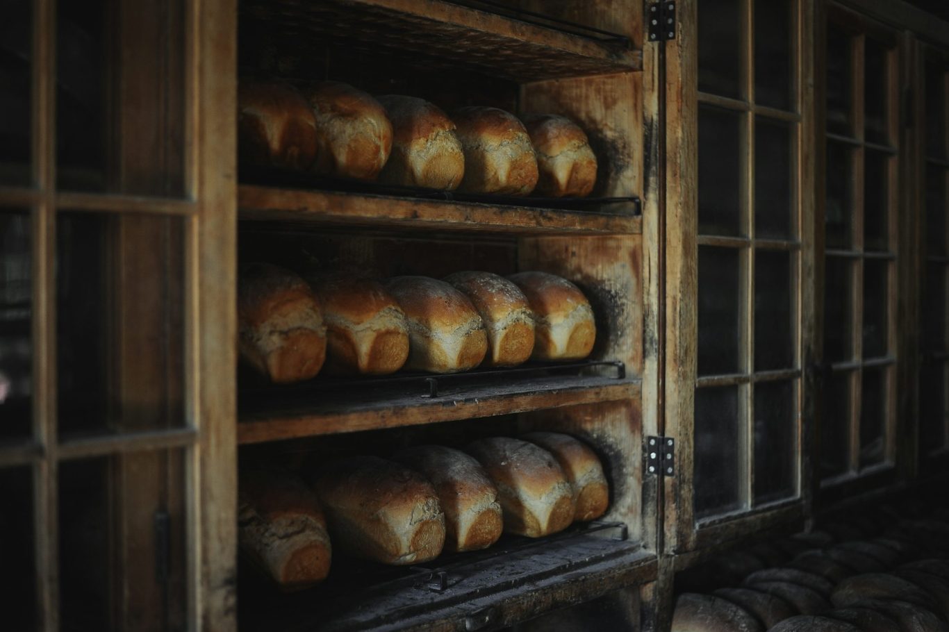 Loaves of bread neatly arranged on shelves in a rustic bakery.